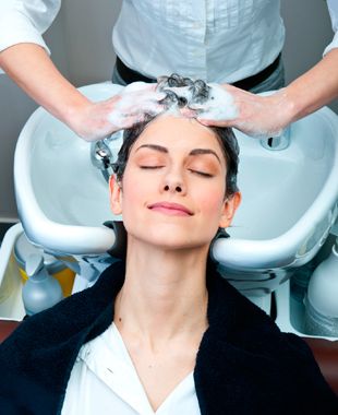 Perruquería Unisex Paquita - Estilista lavandole el cabello a una mujer